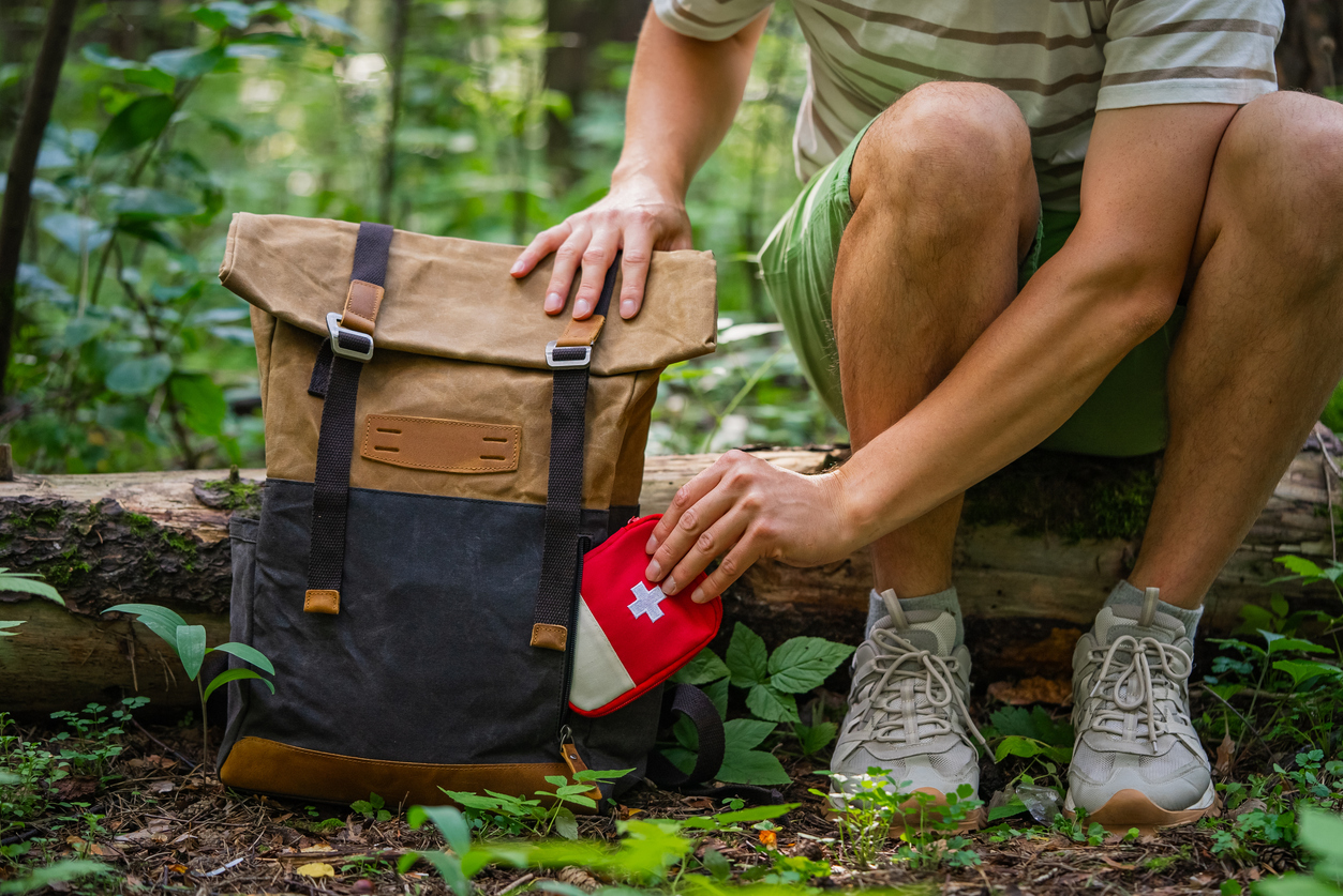 Hiker packing first aid kit into backpack